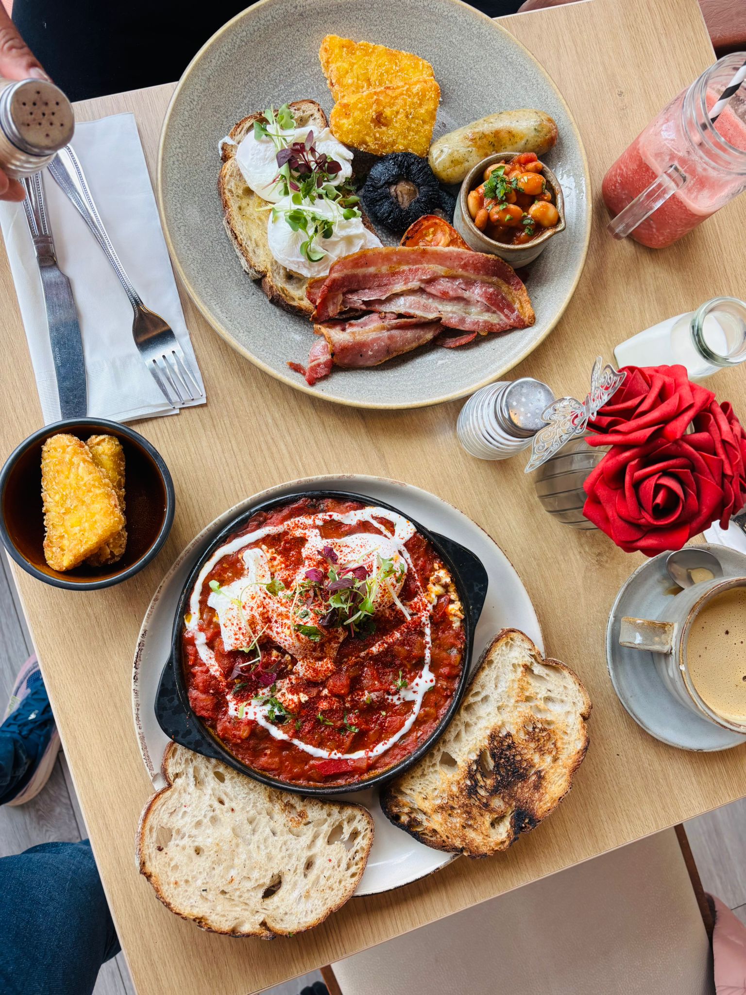 Breakfast with shakshuka, poached eggs, hash browns, bacon, toast, and coffee.