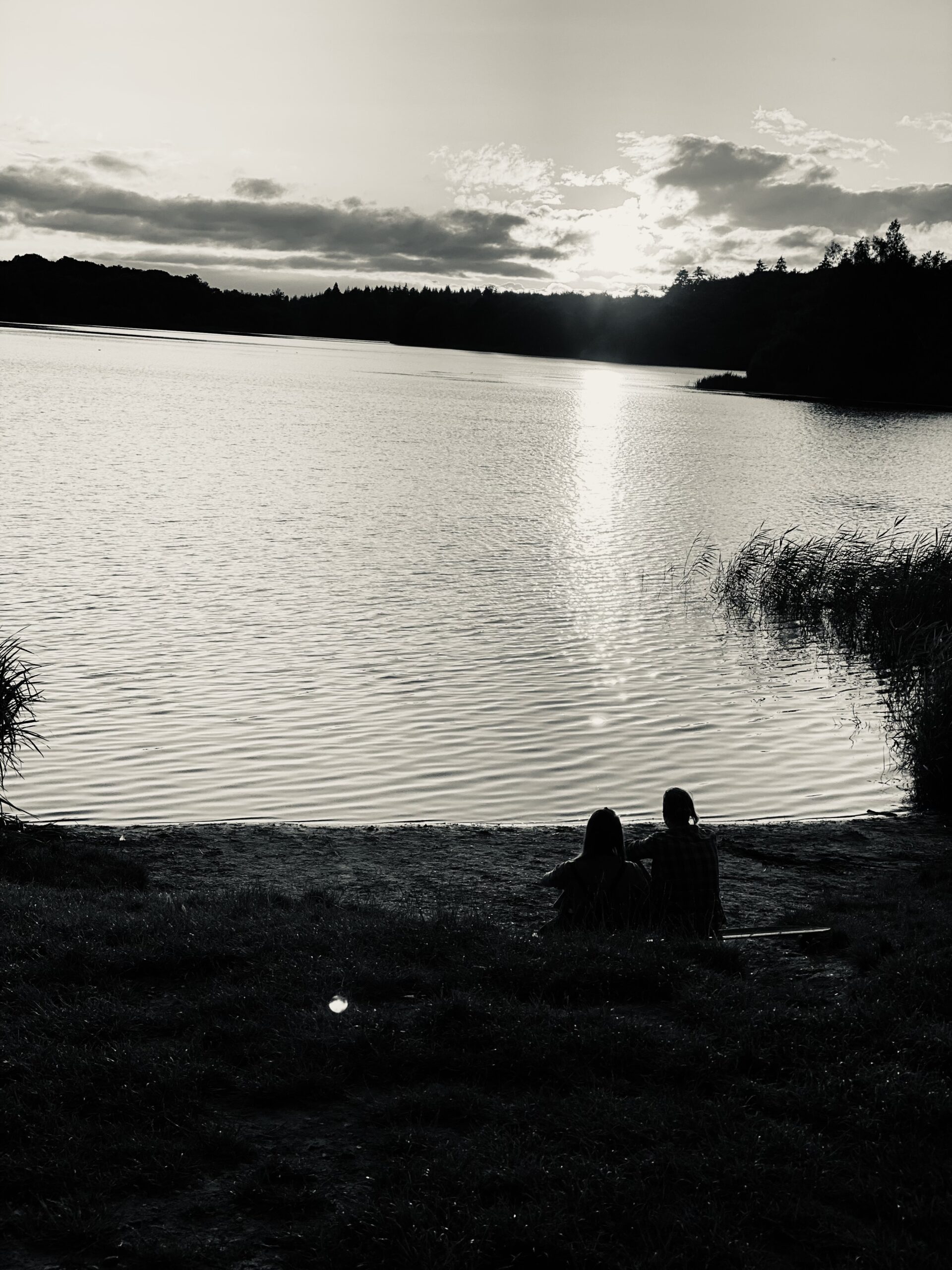 Two women by the lake at sunset.